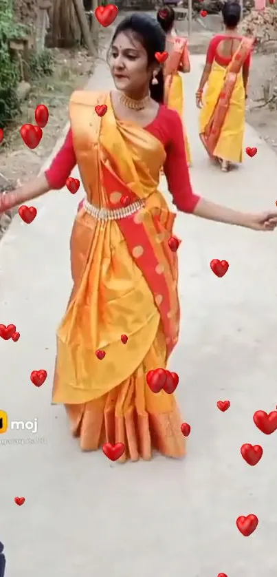 Woman in vibrant orange sari with heart designs dancing elegantly.