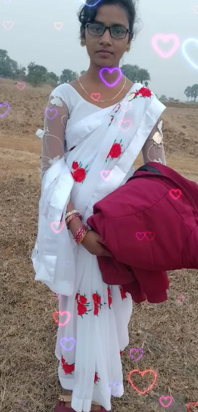 Woman in white saree standing in a field.