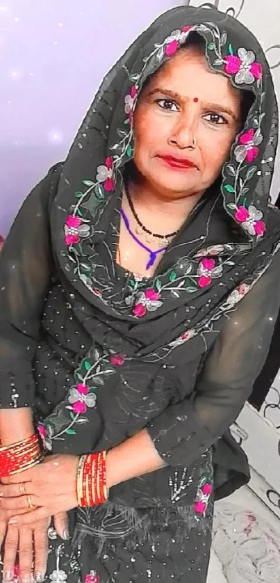 Portrait of a woman in traditional attire with floral embroidery and vibrant bangles.