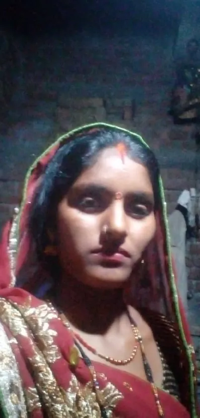 Portrait of a woman in traditional red attire with a brick wall backdrop.