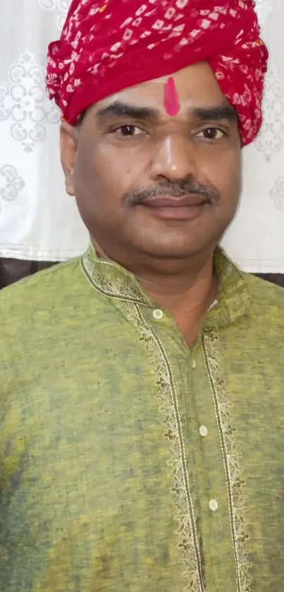 Man in green kurta and red turban, traditional Indian attire.