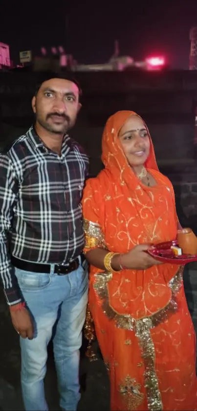 Indian couple in traditional attire during a night event.