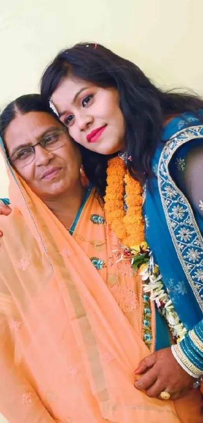 Mother and daughter in traditional Indian attire embracing lovingly.