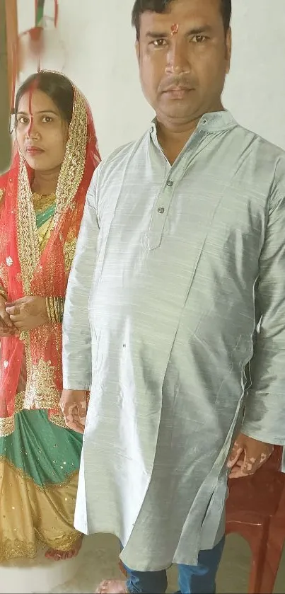 Indian couple in traditional wedding attire with red accents.
