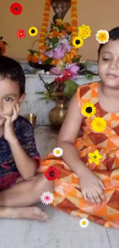 Two kids in vibrant traditional attire sitting indoors with decorations.