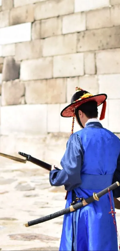 Traditional Korean guard in blue standing by stone wall.