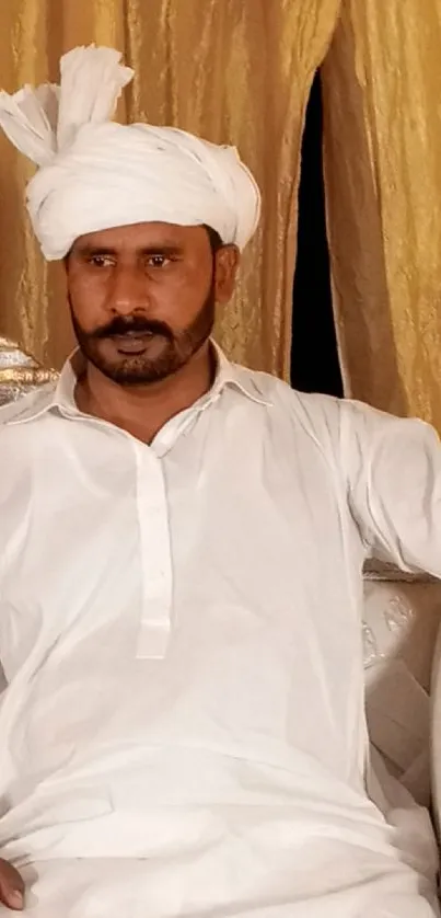 Man in white traditional attire against a golden background.