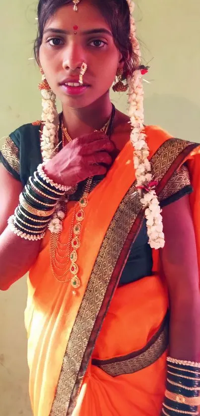 Woman in traditional orange saree with ethnic jewelry.