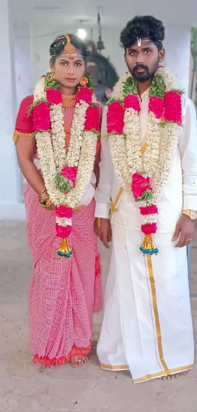 Traditional wedding couple in vibrant attire with floral garlands.