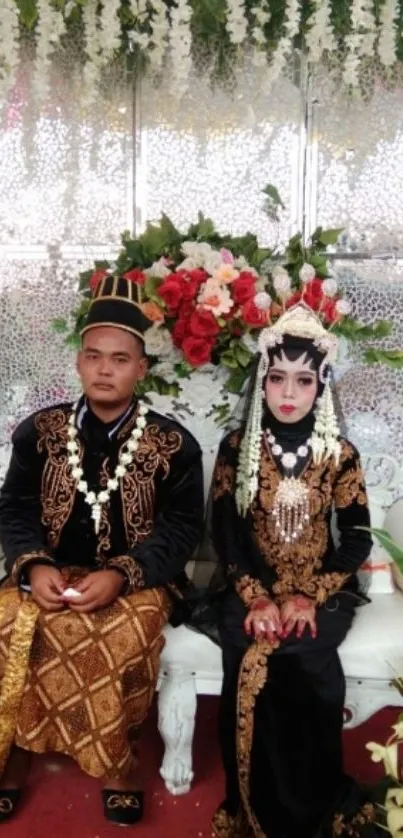 Traditional wedding couple in elegant attire with a floral backdrop.