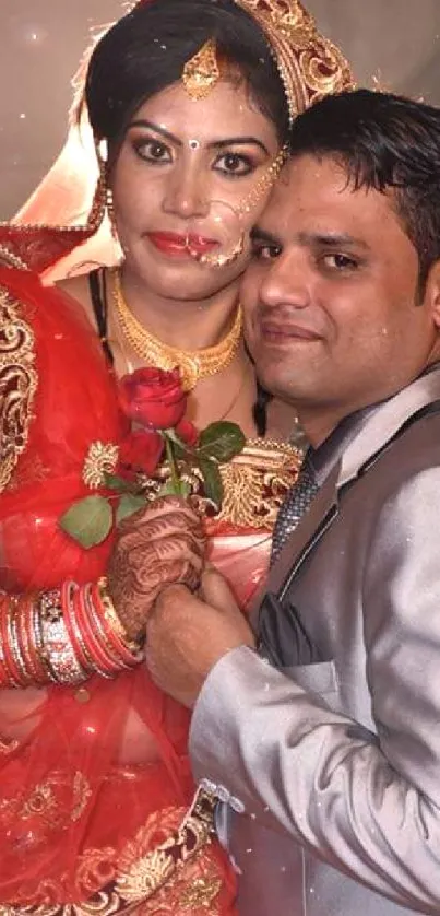 Indian bride and groom in traditional attire holding a rose.