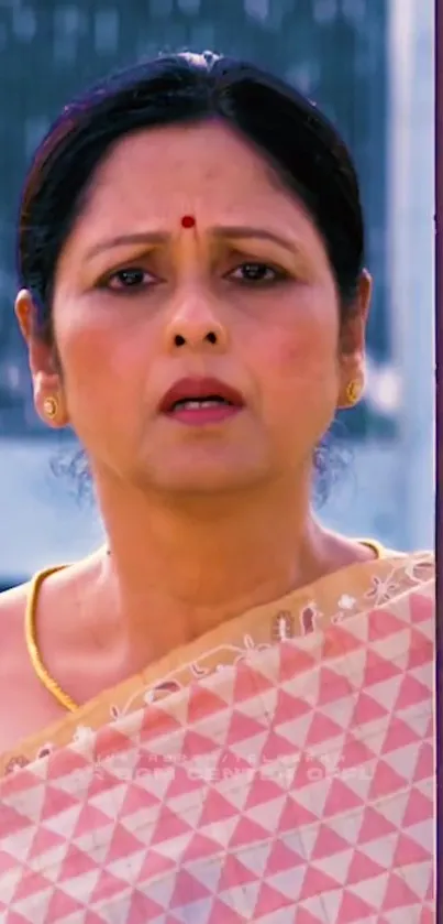 A woman in a pink traditional sari looks intensely forward.