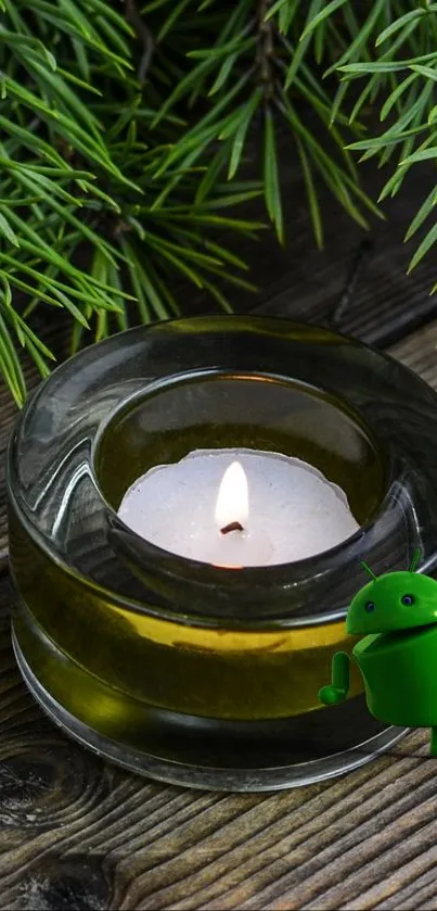 Green candle with Android figure and pine branches on wood.