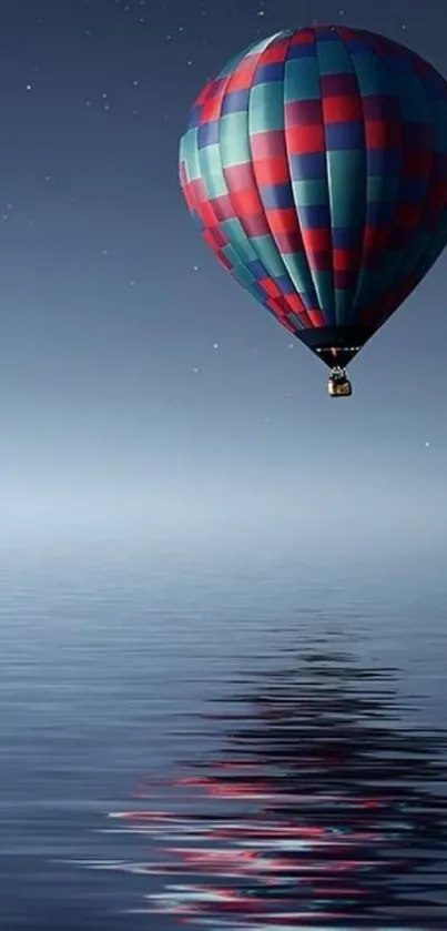 Colorful hot air balloon over calm water at night.