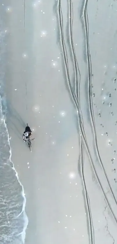 Aerial view of tranquil beach with cyclist, ocean waves, and sandy textures.