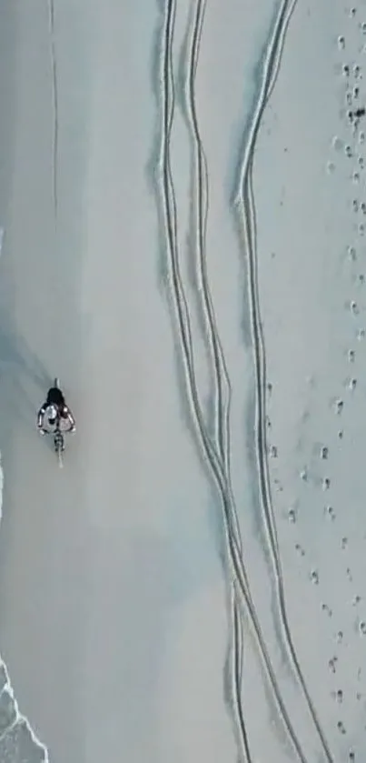 Aerial view of a bike on a sandy beach with ocean waves.