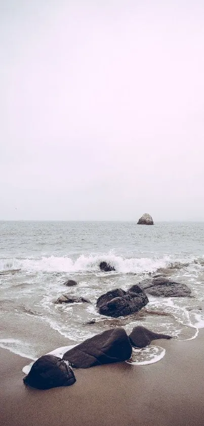 Tranquil beach with rocks and gentle waves under a soft pink sky.