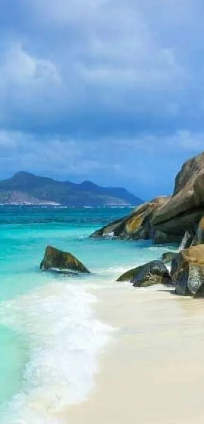 Tropical beach with clear water and rocks under a blue sky.