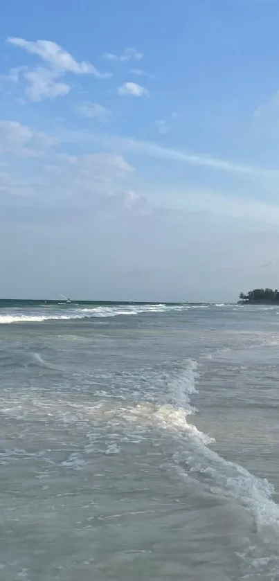 Serene beach scene with calming waves under a blue sky.