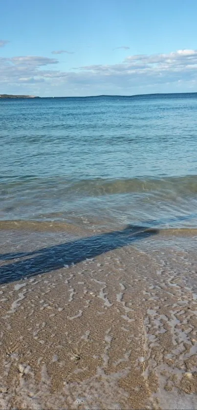 Tranquil beach scene with clear blue water and gentle waves.