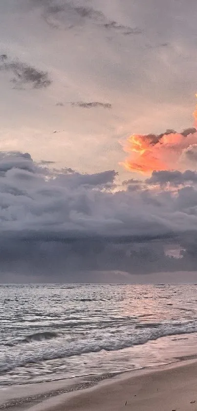 Tranquil beach at sunset with cloudy sky, vibrant colors, and calm waves.