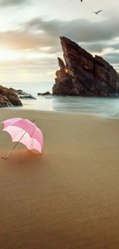 Beach scene with pink umbrella and rock formations under a cloudy sky.