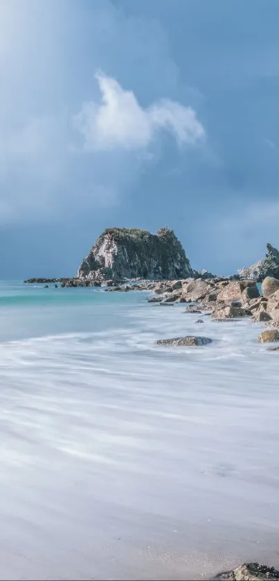 Coastal beach with gentle waves and a rocky shoreline under blue skies.