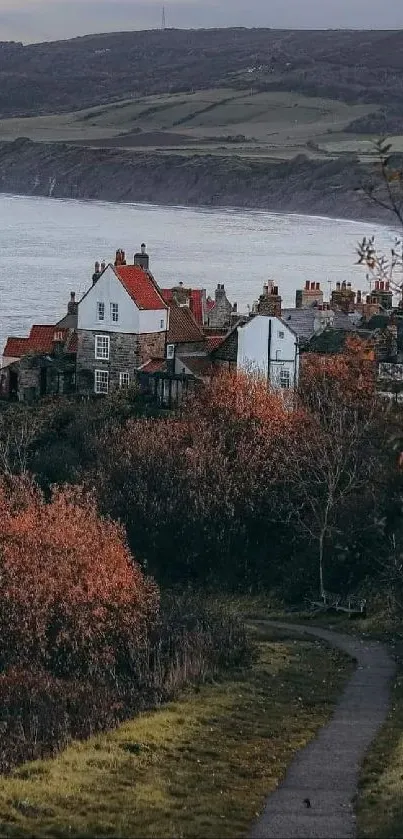 Tranquil autumn village by the sea, with rolling hills in the background.