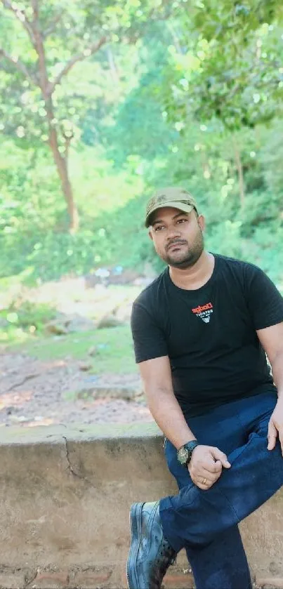 Man sitting on a wall in a lush forest setting.