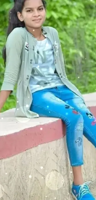 Girl in casual attire sitting on a garden wall.