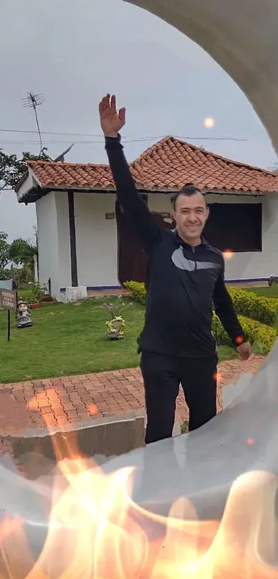 Man posing by house with visible fire effect.