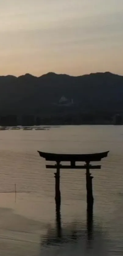 Japanese Torii gate at sunrise over calm lake.