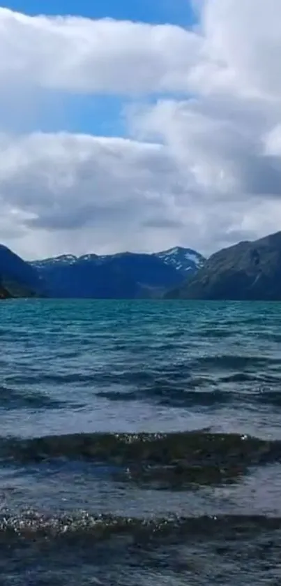 Peaceful lake with mountains under a blue sky.