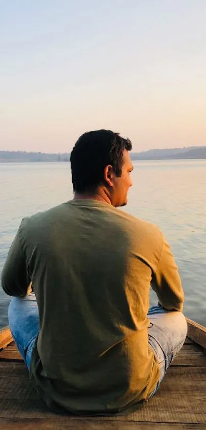 Person sitting on boat facing tranquil lake during sunset