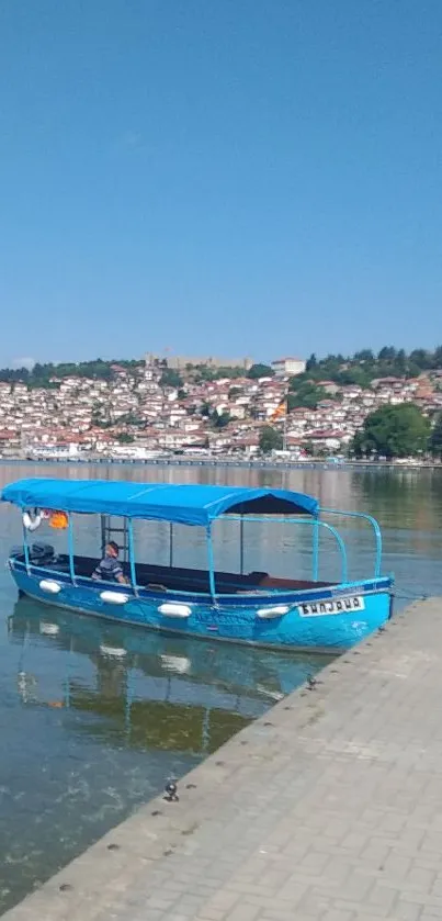 Blue boat floats on a clear lake under a bright blue sky.