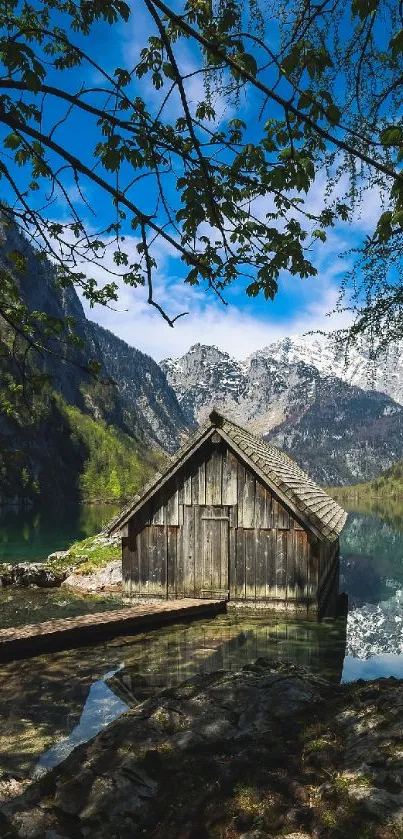 Serene lakeside cabin with mountain reflections under a vibrant blue sky.