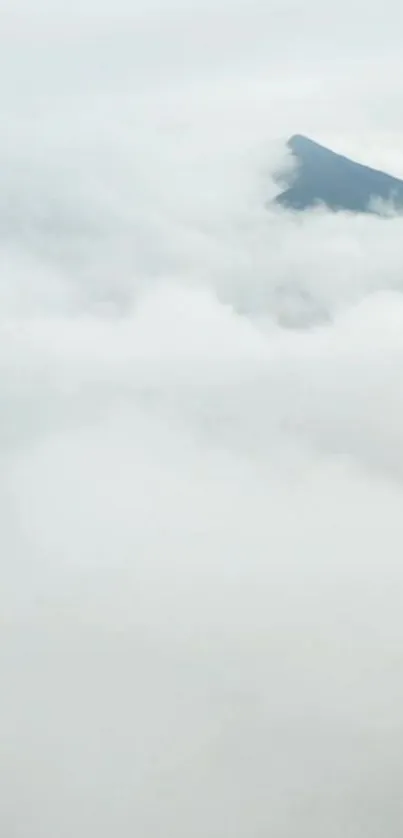 Mountain peak emerging through clouds with tranquil white background.