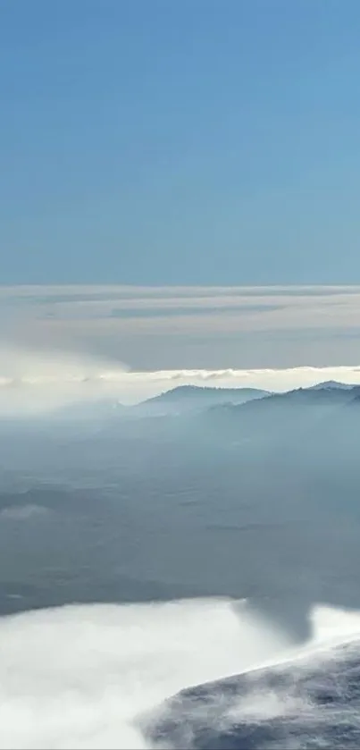 Serene mountain landscape with blue sky and misty hills.