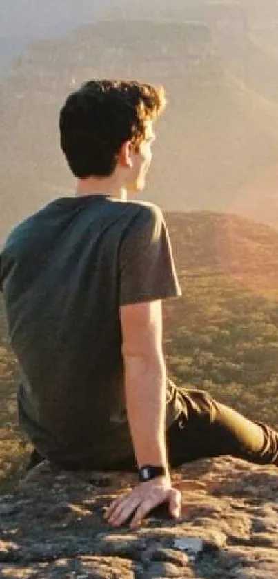 Person sitting on rock gazing at golden mountain landscape.