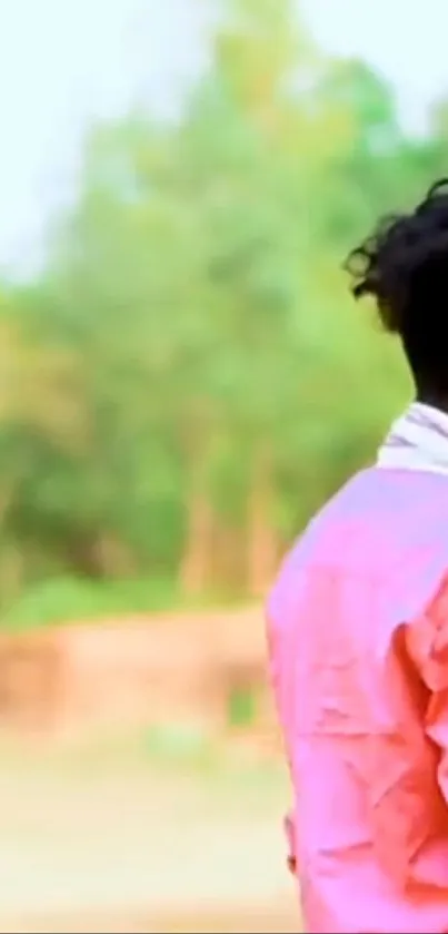 Man in pink shirt against a lush green background, exuding calm vibes.