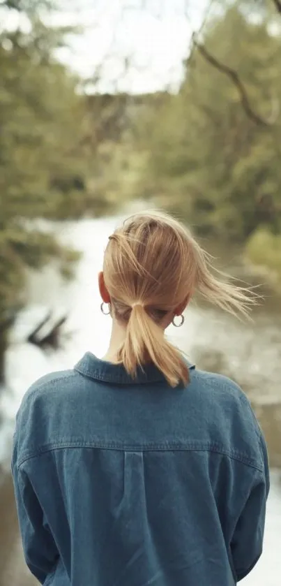 A tranquil scene of a person looking over a serene river surrounded by greenery.