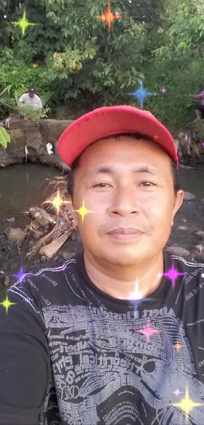 Man in red cap takes selfie by tranquil forest stream.