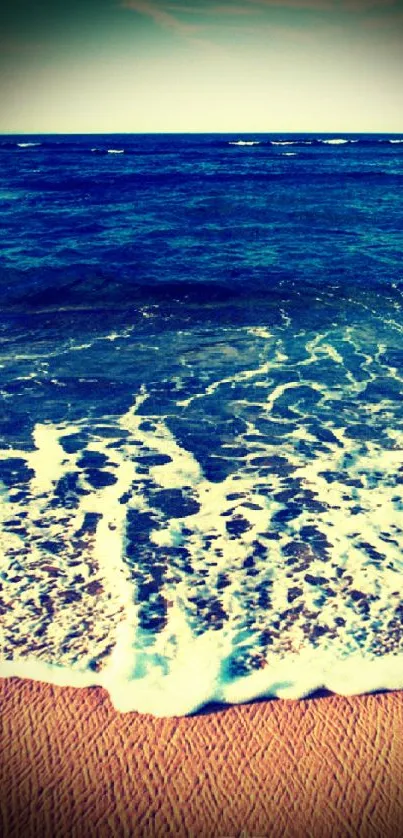 Peaceful beach with waves and sandy shore under a deep blue sky.