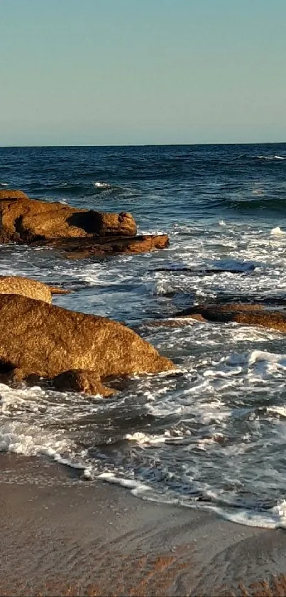 Ocean view with rocks and gentle waves on a sunny beach.