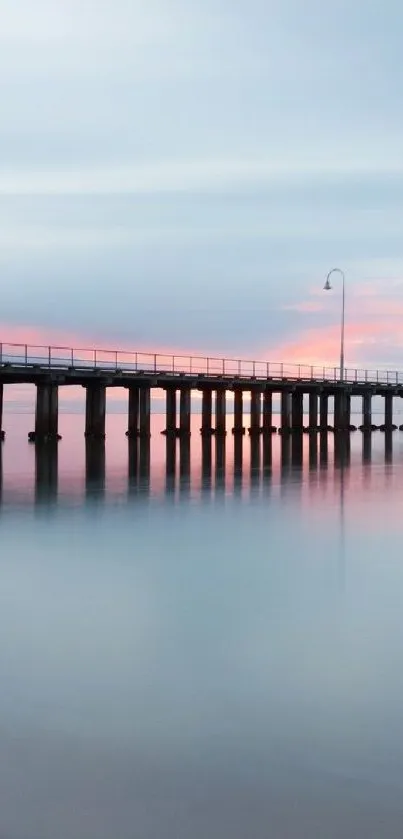 Tranquil pier over calm ocean during sunset with pastel sky reflection.