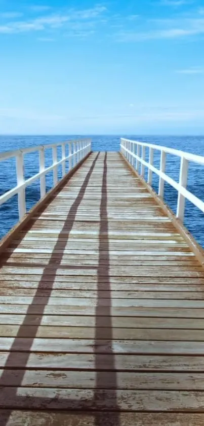 A tranquil pier extending into a calm blue ocean under a clear sky.