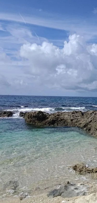 Tranquil ocean view with rocky shore and blue sky wallpaper.