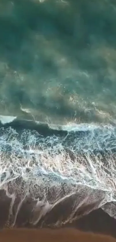 Aerial view of ocean waves on a sandy beach, captured in a tranquil mobile wallpaper.