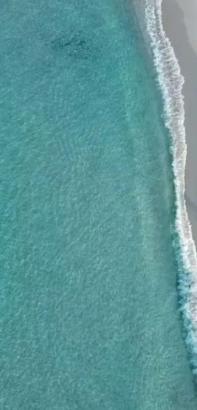 Aerial view of tranquil ocean waves meeting a sandy shore in calming blue hues.