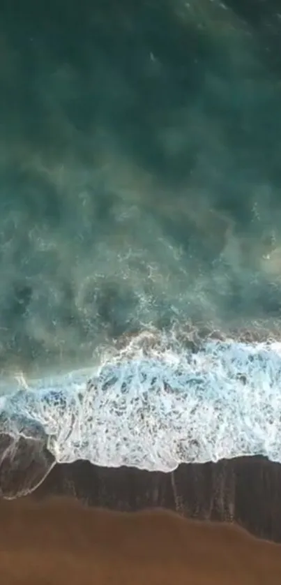 Aerial view of ocean waves meeting sandy beach, creating tranquil scenery.